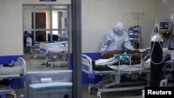 A member of the medical staff dressed in a protective suit treats a coronavirus disease patient inside the COVID-19 ICU of Machakos Level 5 Hospital, in Machakos, Kenya, Oct. 28, 2020. Picture taken Oct. 28, 2020.
