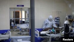 A member of the medical staff dressed in a protective suit treats a coronavirus disease patient inside the COVID-19 ICU of Machakos Level 5 Hospital, in Machakos, Kenya, Oct. 28, 2020. Picture taken Oct. 28, 2020.