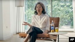 In this image made from an undated commercial video, South Korean actor Youn Yuh-jung “Minari”, 74 years old, sits in the beer company Oriental Brewery's latest advertising campaign.