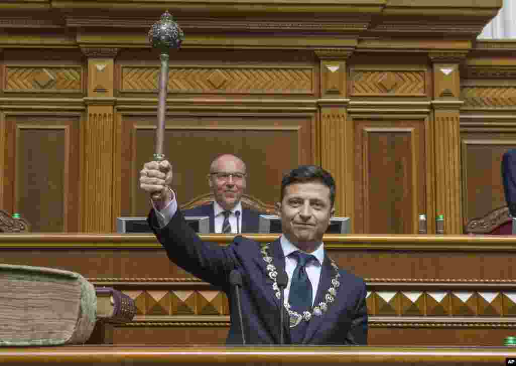 The new Ukrainian President Volodymyr Zelenskiy holds up a mace, the Ukrainian symbol of power, during his inauguration ceremony in Kyiv.