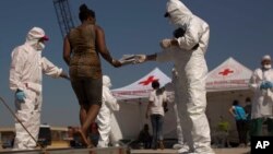 A woman from Nigeria receives a pair of shoes from Italian aid workers as she leaves the Golfo Azzurro rescue vessel upon their arrival at the port of Pozzallo, south of Sicily, June 17, 2017. 