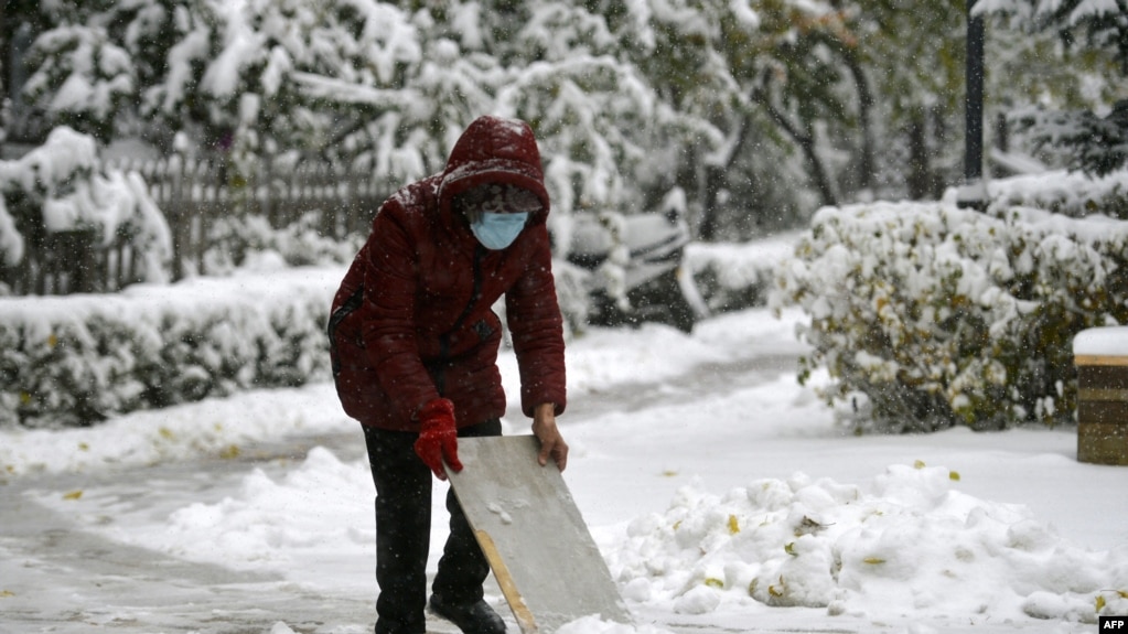 A resident clears snow from a street during snowfall in Shenyang, in China's northeastern Liaoning province on November 6, 2023. (Photo by AFP) / CHINA OUT