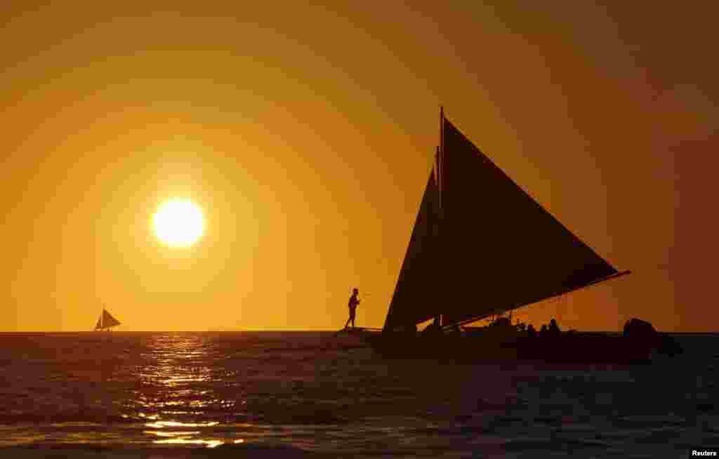 Tourists sail along the island of Boracay, central Philippines, at sunset, Jan. 17, 2016.