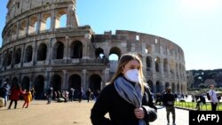 Para turis mengenakan masker saat mengunjungi Coliseum di Roma, Italia (foto: ilustrasi). 