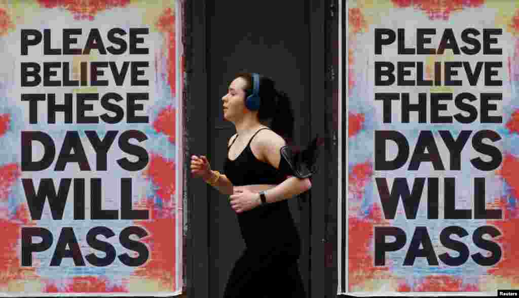 A person runs past posters with a message of hope, as the spread of the coronavirus disease (COVID-19) continues, in Manchester, Britain.