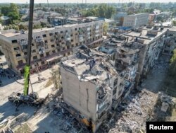 Spasioci rade teškom mehanizacijom na mestu zgrade uništene tokom ruskog raketnog udara, u Pokrovsku, Donjecka oblast, Ukrajina 8. avgusta 2023.