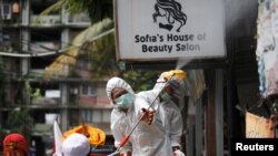 Seorang petugas Palang Merah Indonesia menyemprotkan carian disinfektan di kampung padat penduduk di tengah wabah virus corona (COVID-19) di Jakarta, 4 April 2020. (Foto: Reuters)