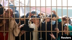 Women wait to receive tokens needed to apply for a Pakistani visa in Jalalabad, Afghanistan.