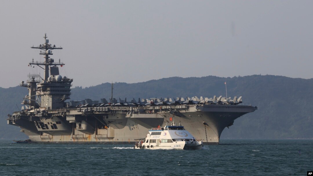 A Vietnamese passenger boat sails past U.S aircraft carrier USS Carl Vinson as it docks in Danang bay, Vietnam on Monday, March 5, 2018. (AP Photo/ Hau Dinh)