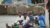 FILE - Indigenous tobacco farmers, with their children, wait to sell their tobacco, at Boka Tobacco auction floors, in Harare, Zimbabwe, May 14, 2013. 