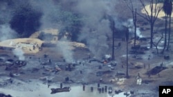 FILE: In this Thursday, March 24, 2011 photo, smoke rises from an illegal oil refinery in Ogoniland, outside Port Harcourt, in Nigeria's Delta region. 