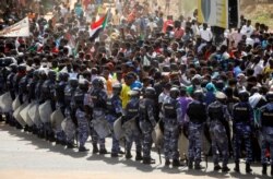 Riot police officers hold their position on June 30, 2020, against protesters near the Parliament buildings in Khartoum.