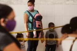 A woman with her children, wearing face masks amid the spread of the new coronavirus, wait at a health center in the Juan Diaz neighborhood, an area with high contagion levels of COVID-19, in Panama City, July 16, 2020.