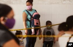 A woman with her children, wearing face masks amid the spread of the new coronavirus, wait at a health center in the Juan Diaz neighborhood, an area with high contagion levels of COVID-19, in Panama City, July 16, 2020.