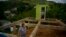 FILE - A woman poses for a portrait between the beams of her home being rebuilt after it was destroyed by Hurricane Maria one year ago in the San Lorenzo neighborhood of Morovis, Puerto Rico, Sept. 8, 2018.