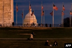 FILE - The US Capitol Building is seen past the Washington Monument as the sun sets on December 26, 2020 in Washington, DC. Lawmakers will meet on Jan. 6 to confirm the presidential election results.