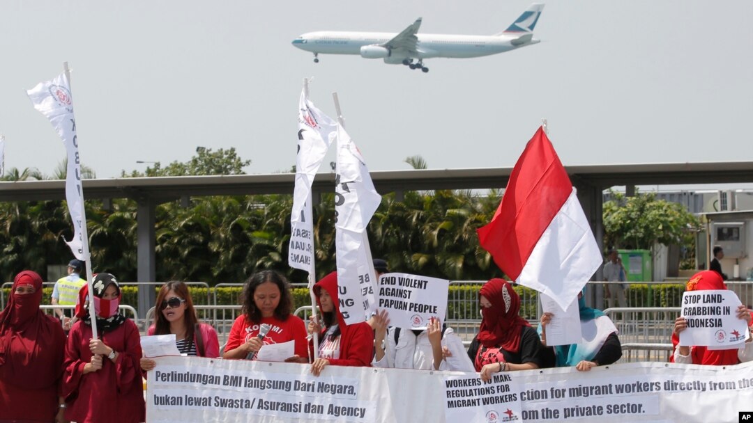 Para aktivis pekerja migran Indonesia memegang poster-poster dan bendera Indonesia dekat tempat pertemuan Presiden Joko Widodo dan warga Indonesia di Hong Kong, 30 April 2017. (Foto: AP)