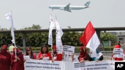 Para aktivis pekerja migran Indonesia memegang poster-poster dan bendera Indonesia dekat tempat pertemuan Presiden Joko Widodo dan warga Indonesia di Hong Kong, 30 April 2017. (Foto: AP)