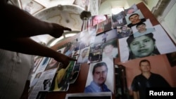 A parishioner points at photographs of missing persons during a mass to commemorate the International Day of the Victims of Enforced Disappearances in San Francisco de Asis church in Tala, in Jalisco state, Mexico, Aug. 31, 2014.