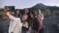 Sejumlah wisatawan domestik berswafoto dengan latar belakang Gunung Merapi, Yogyakarta, 6 Agustus 2019. (Foto: Slamet Riyadi/AP)