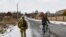 FILE - A Ukrainian serviceman patrols a street near the frontline with Russia-backed separatists in Verkhnotoretske village in Yasynuvata district, Donetsk region, eastern Ukraine, Jan. 22, 2022.