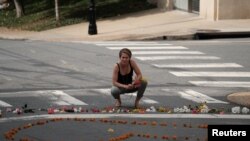 A woman kneels at a makeshift memorial for the victims of a car that plowed into counter-protesters after a "Unite the Right" rally organized by white nationalists in Charlottesville, Virginia, Aug. 13, 2017. 