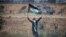 A woman holding a Palestinian flag gestures in front of Israeli forces during a protest marking the 71st anniversary of the 'Nakba', or catastrophe, at the Israel-Gaza border fence, in the southern Gaza Strip, May 15, 2019.