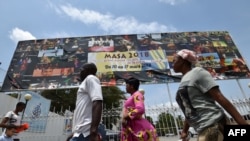 Quelques personnes marchent devant une pancarte publicitaire géante du Marché des Arts du Spectacle Africain d'Abidjan (Masa), à Abidjan, le 9 mars 2018.