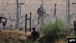 Un migrante que busca asilo en Estados Unidos es vigilado por un miembro de la Guardia Nacional de Texas después de cruzar el río Grande, visto desde Ciudad Juárez, estado de Chihuahua, México, el 5 de junio de 2024.