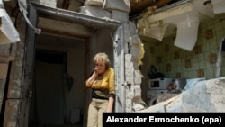 FILE - A local woman reacts next to her destroyed home after shelling in pro-Russian rebel-controlled Staromykhaylivka village near of Donetsk, Ukraine, 24 May 2016.