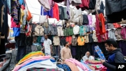 FILE - Garment sellers wait for customers beside an overpass in Kolkata, India, Thursday, Feb. 1, 2024. 