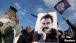 FILE - Followers of jailed Kurdish militant leader Abdullah Ocalan hold up a poster of him in Diyarbakir, Turkey, Feb. 27, 2025. 