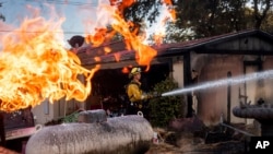 Le pompier Nolan Graham pulvérise de l'eau autour d'un garage lors d'un incendie à Clearlake, en Californie, le 8 septembre 2024. AP / Noah Berger