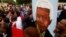 A group of mourners carrying a picture of South African leader Nelson Mandela, sing and dance outside his Johannesburg home, Dec. 6, 2013, after the freedom fighter passed away Thursday night after a long illness.