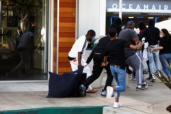 FILE - People run with a bag of items during nationwide unrest following the death in Minneapolis police custody of George Floyd, in Long Beach, Calif., May 31, 2020.