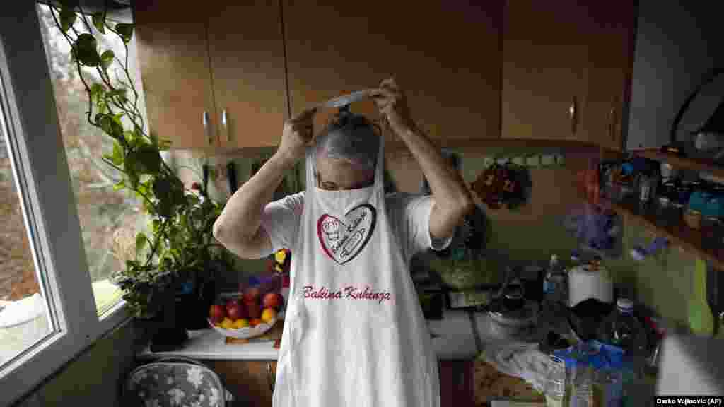 Jelena Petrovic puts on an apron as her husband returns with groceries.