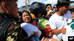 A woman and her child plead from the frantic crowd to be prioritized on an evacuation flight in Tacloban, central Philippines, Nov. 14, 2013.