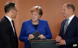 FILE - German Chancellor Angela Merkel, German Foreign Minister Heiko Maas, left, and German Finance Minister Olaf Scholz talk as they arrive for the weekly Cabinet meeting at the chancellery in Berlin, May 15, 2019.