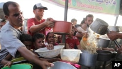 Palestinianos recebem comida antes do feriado de Eid al-Adha em Khan Younis, na Faixa de Gaza, no sábado, 15 de junho de 2024.