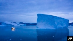 FILE - In this Aug. 15, 2019, photo, a boat navigates at night next to large icebergs in eastern Greenland. 