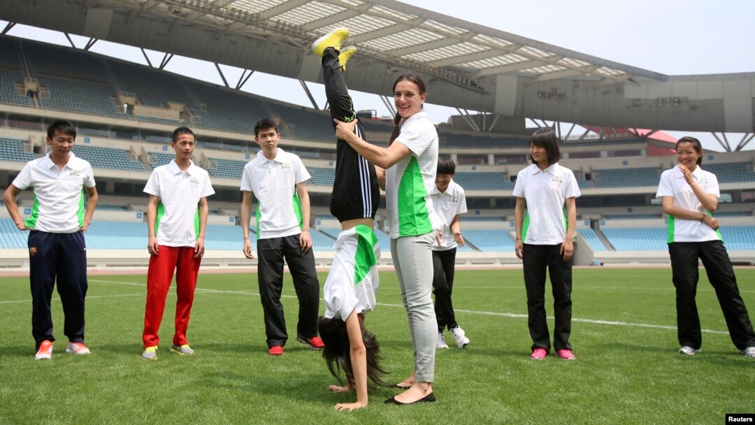 Atlet lompat galah Rusia Yelena Isinbayeva (depan, kanan), Duta Olimpiade Pemuda, membantu atlet muda China berlatih di pusat olahraga di Nanjing, tuan rumah Olimpiade Pemuda 2014. (Reuters/China Daily)