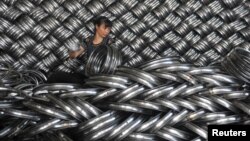 FILE - A woman works on packaging bicycle rim steels for export at a workshop of a company manufacturing sports equipments in Hangzhou, Zhejiang province, China, June 4, 2018. 