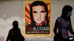 Transeúntes pasan frente a un cartel que pide la libertad del empresario colombiano y enviado especial venezolano Alex Saab, en Caracas, el 9 de septiembre de 2021. La justicia federal de EEUU acusa a Saab de lavado de dinero. 
