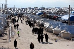 FILE - Women walk through al-Hol displacement camp in Hasaka governorate, Syria, April 1, 2019.