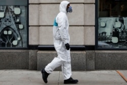 FILE - A man wears personal protective equipment (PPE) as he walks on First Avenue, during the coronavirus disease outbreak, in New York City, March 31, 2020.