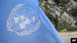 FILE - A United Nations peacekeeper is seen standing on patrol behind a U.N. flag.