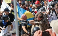 In this Aug. 12, 2017 file photo, white nationalist demonstrators - including three members of the Rise Above Movement - clash with counter demonstrators at the entrance to Lee Park in Charlottesville, Va.