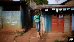 FILE - A man checks his phone in Kibera, Africa's largest slum, in Nairobi, Kenya, March 6, 2013. Experts say mobilizing slum dwellers is one solution to reducing the challenges in African cities.