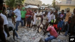 A man digs with a stone through the rubble of a house destroyed by the most recent earthquake in Les Cayes, Haiti, Aug. 15, 2021.