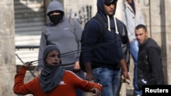 Un jeune palestinien lance une pierre contre les forces de sécurité israéliennes au cours des affrontements à Hébron, 29 octobre 2015. REUTERS/Mussa Qawasma